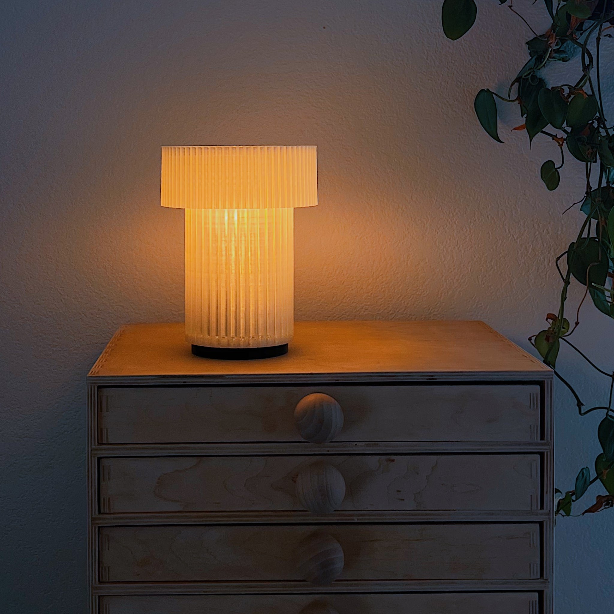 Image of Mini Drum Lamp displaying a warm glow on a nightstand