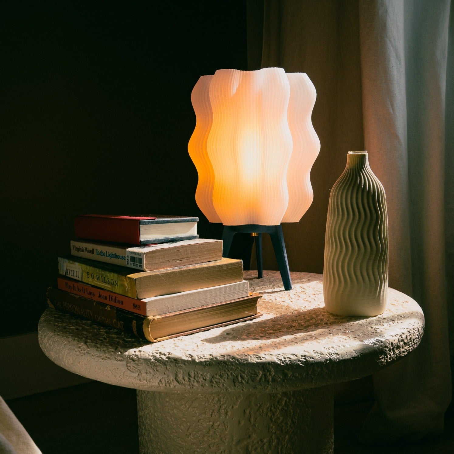 Wavy Lamp in matte black on bedside table with books