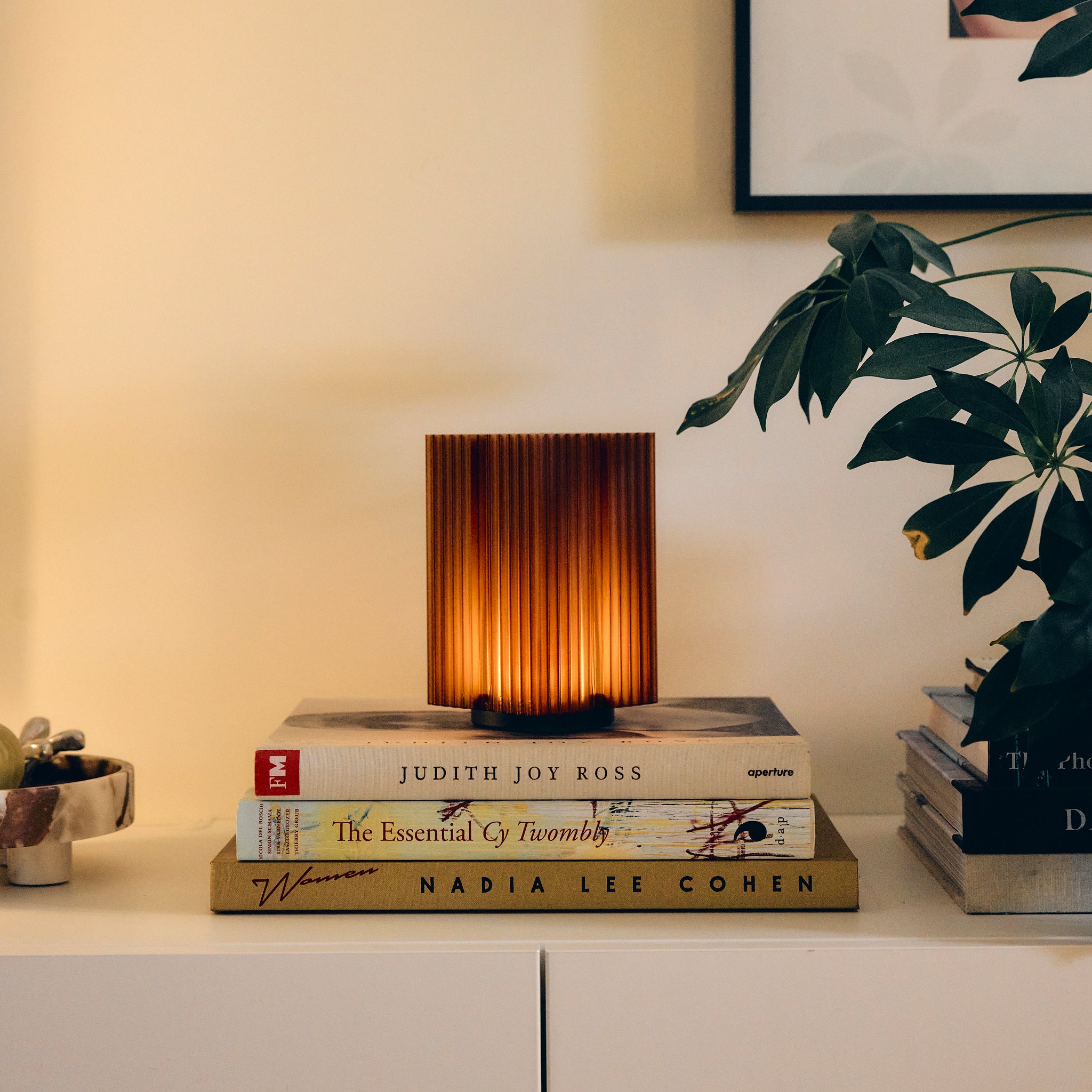Cordless mini brut lamp in amber on stack of books