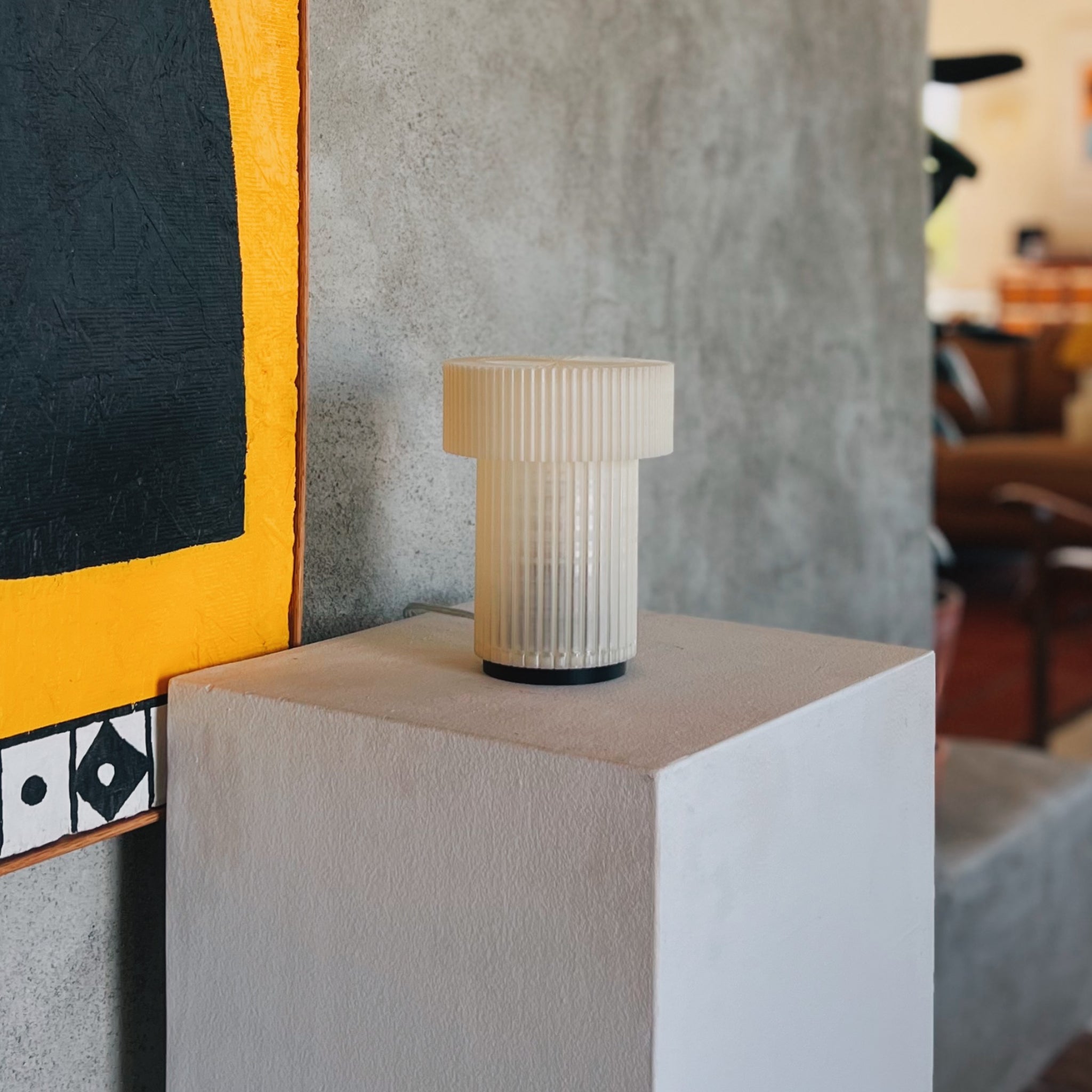 Image of Mini Drum Lamp on a cement shelf in front of a cement wall
