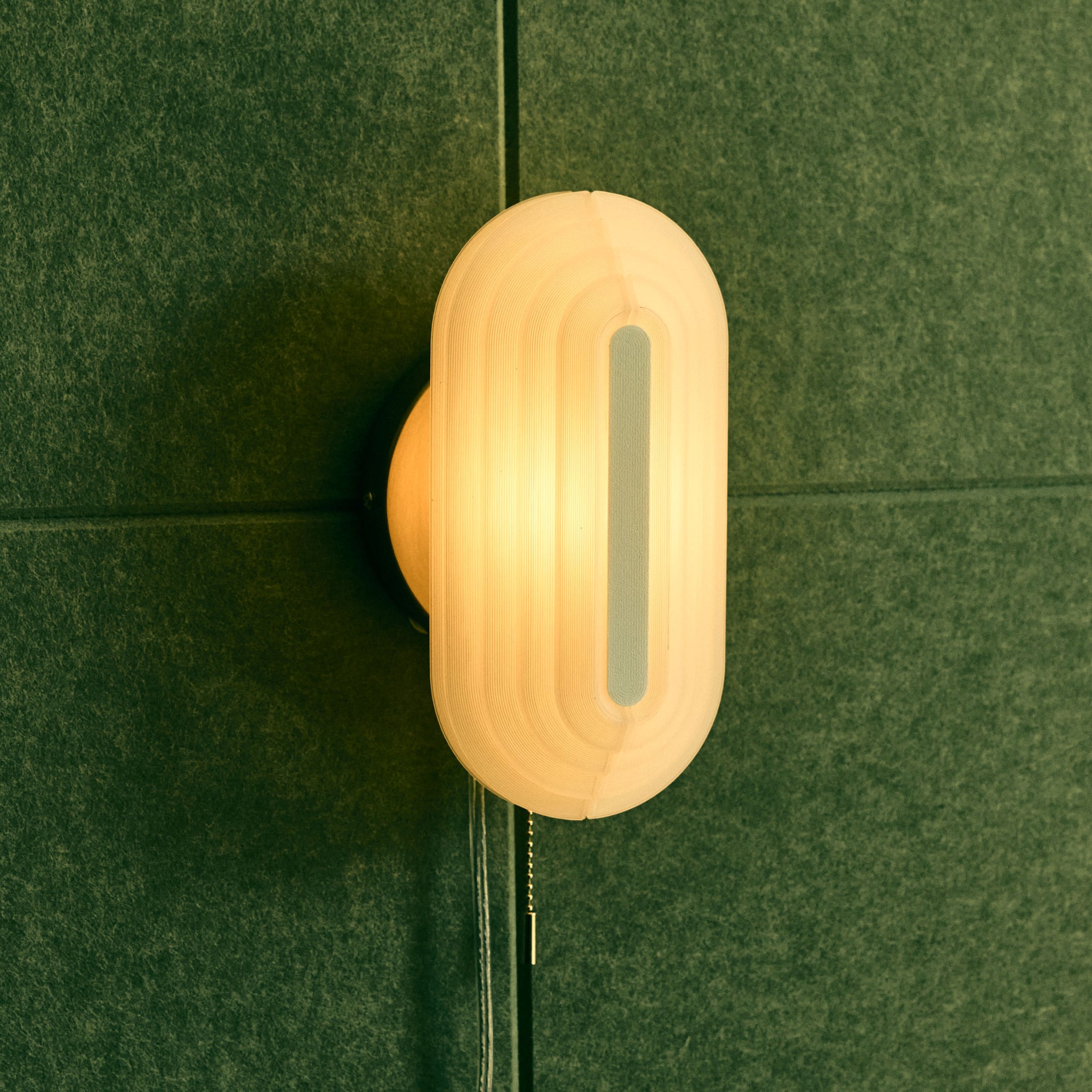 Pill Sconce from the side on green background