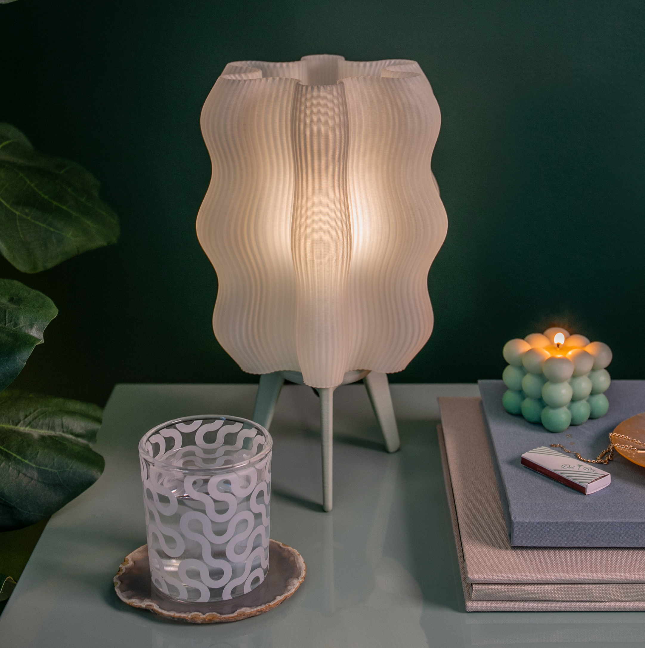 Wavy Lamp in mint on side table with books and candle next to plant
