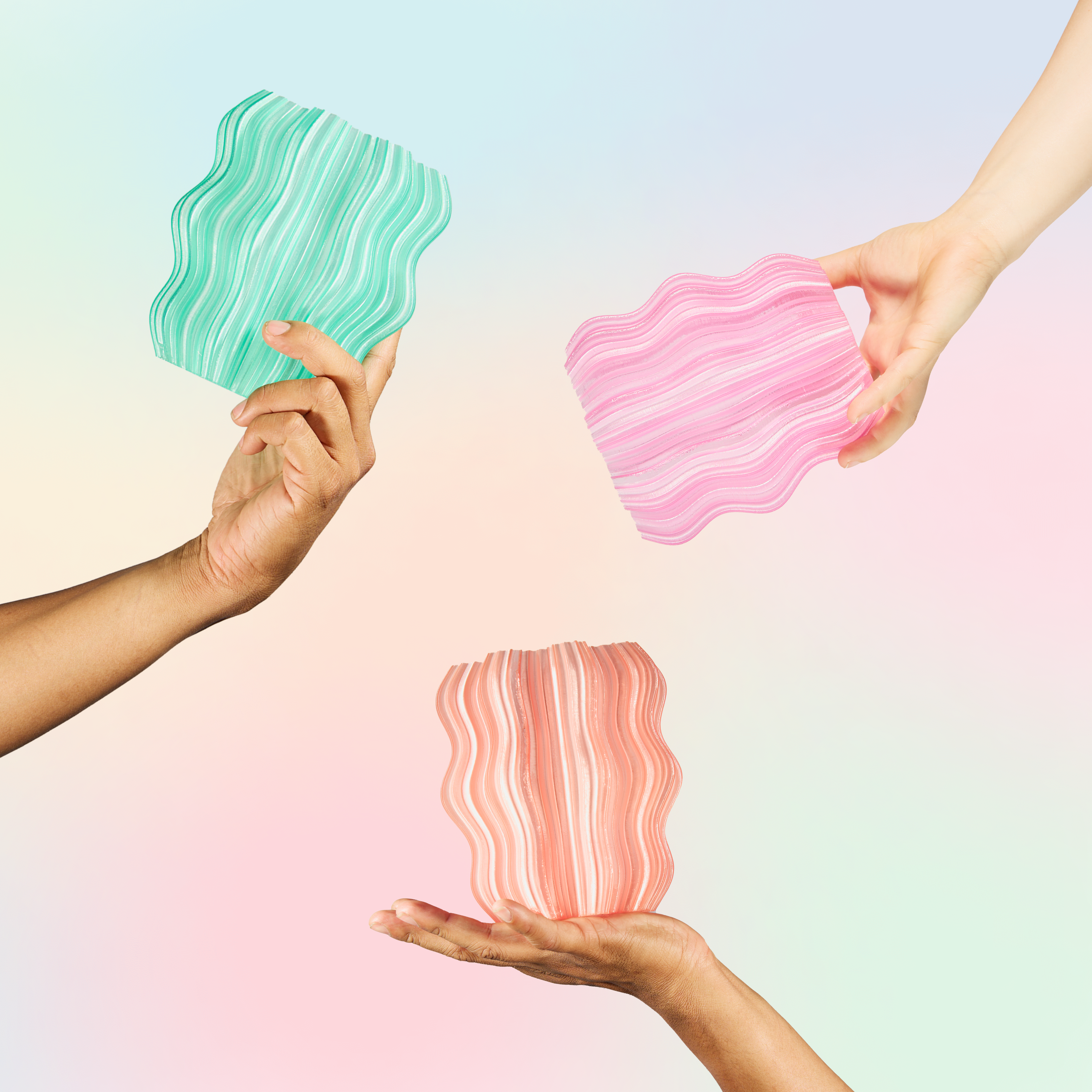 Three hands holding pink, peach, and seafoam Mini Wavy Lamps on multicolor background