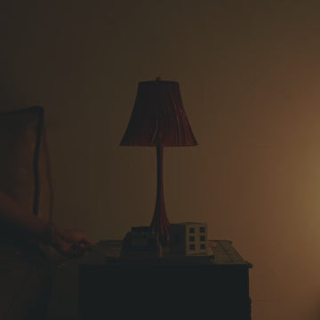 Pleat Lamp in Amber on bedside table