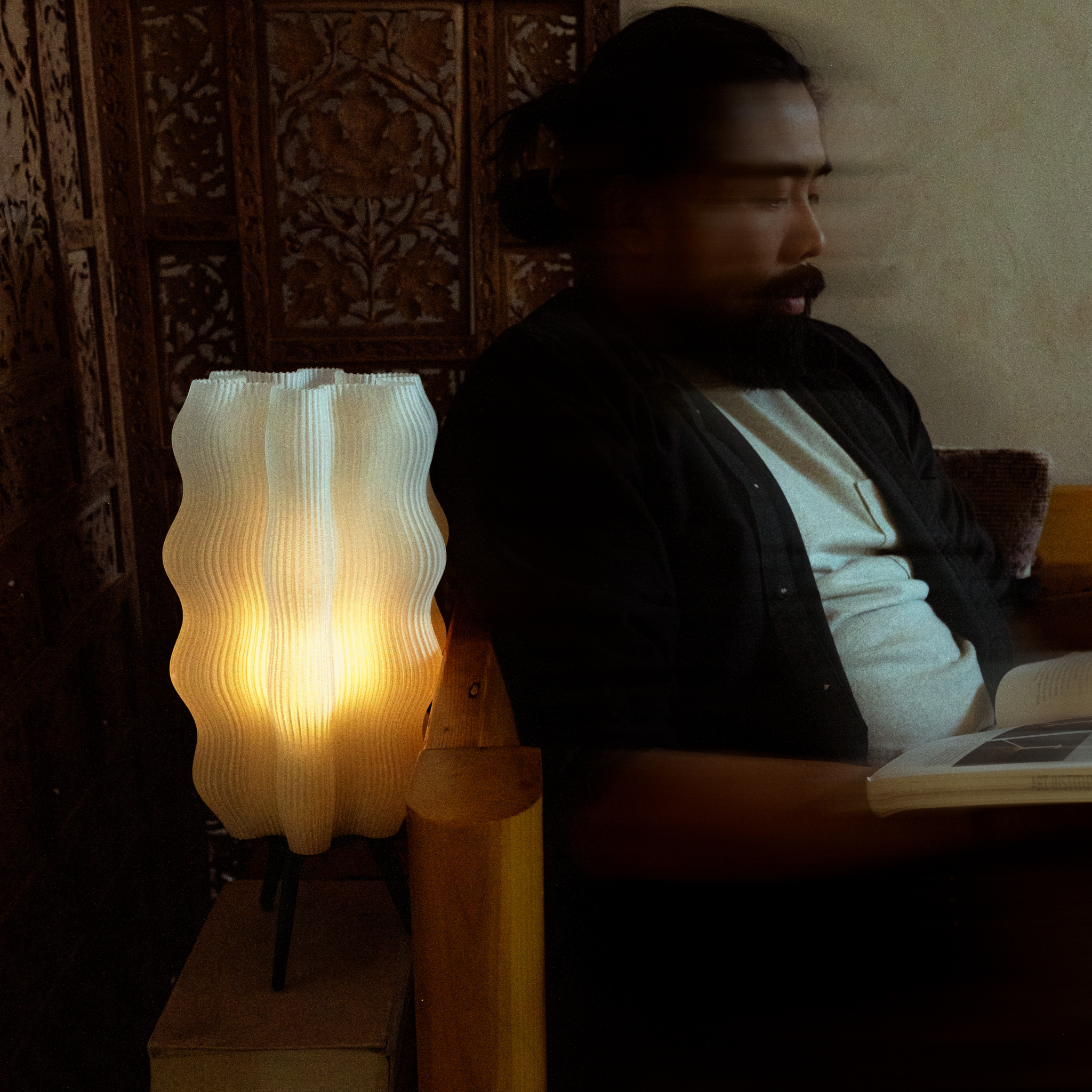 Tall Wavy Lamp in Matte Black on side table with man reading